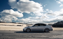Заниженный Subaru Legacy на фоне русского поля и облачного неба
